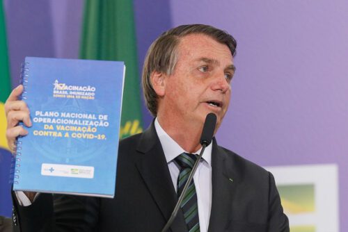 Jair Bolsonaro holding up Brazil's national vaccination plan.