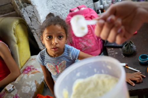 A small girl looks at spoonful of food is offered to her from a container, showing the impact of US sanctions on Cuba.