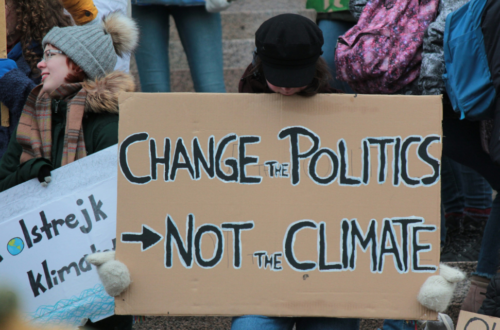 Rising Cost of Debt: An Obstacle to Achieving Climate and Development Goals. A person holding a large cardboard sign that reads 