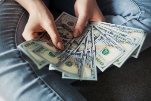 A person displays a fanned-out stack of U.S. one hundred dollar bills dispelling myths about the saving rate.