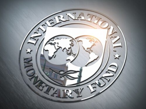 A silver embossed seal of the IMF featuring a world map with North America, South America, Africa, and Europe visible. The text 