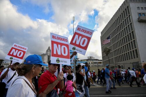 Cubans walk past the US embassy as they march along Havana's promenade on December 20, 2024, during a demonstration against the blockade and Cuba's remaining on the list of countries that sponsor terrorism. Several hundred thousand Cubans, led by communist leader Raul Castro, marched on Friday in front of the US embassy in Havana to demand an end to Washington's blockade, a month before Donald Trump returns to command the White House. (Photo by YAMIL LAGE / AFP) (Photo by YAMIL LAGE/AFP via Getty Images)