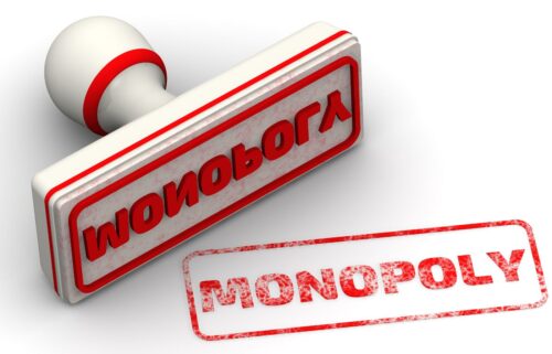 A red rubber stamp with a white handle and red trim is shown. The stamp is imprinted with the word MONOPOLY in raised, reversed letters. Below the stamp, the inked imprint reads MONOPOLY in red capital letters on a white background.