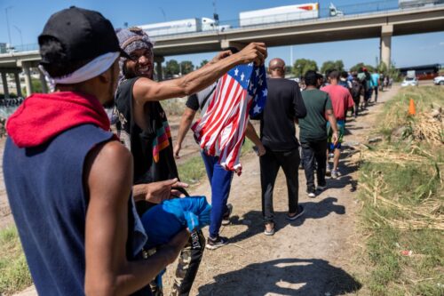 EAGLE PASS, TEXAS - SEPTEMBER 28: An immigrant from Venezuela displays a flag after crossing the Rio Grande from Mexico into the United States on September 28, 2023 in Eagle Pass, Texas. A surge of asylum seeking migrants crossing the U.S. southern border has put pressure on U.S. immigration authorities, reaching record levels in recent weeks. (Photo by John Moore/Getty Images)