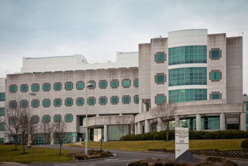 Modern institutional building with large glass windows, curved entrance, and sign reading 