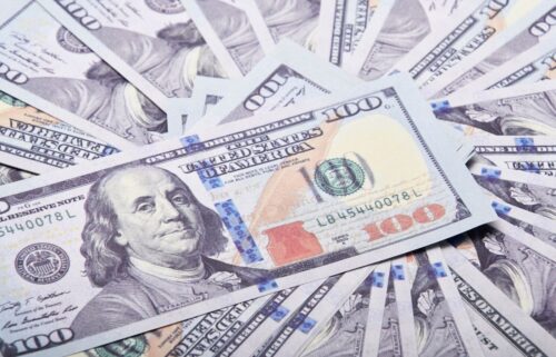 A fan of U.S. $100 bills showcases Benjamin Franklin's portrait. The crisp blue security strip and vibrant details convey prosperity and abundance.