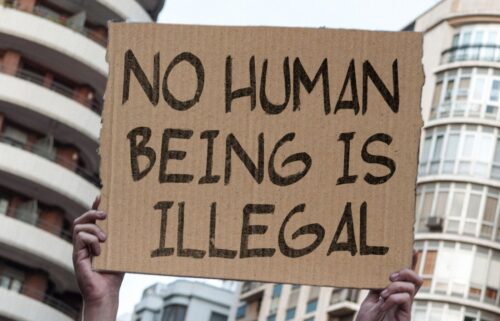 Person holding a cardboard sign that reads 