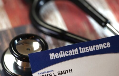 A blue Medicaid Insurance card prominently displayed beside a stethoscope on a wooden background, conveying themes of healthcare and coverage.