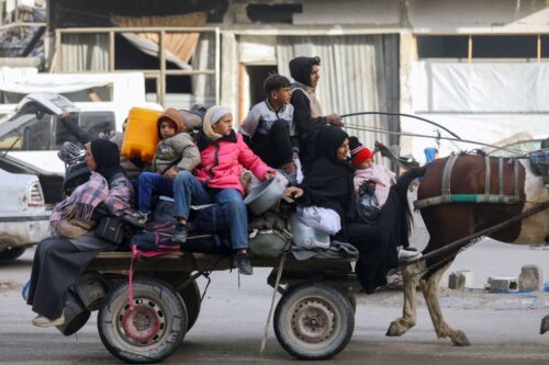 A family with children and belongings is crowded on a horse-drawn cart. They appear somber and bundled in clothing, suggesting a journey or displacement.due to sanctions. (Photo by Youssef Alzanoun / Middle East Images / Middle East Images via AFP) (Photo by YOUSSEF ALZANOUN/Middle East Images/AFP via Getty Images)