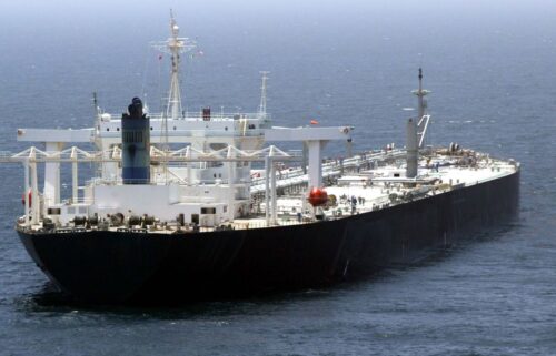 A large Russian oil tanker sails through calm, deep blue waters. The ship's deck is cluttered with equipment.