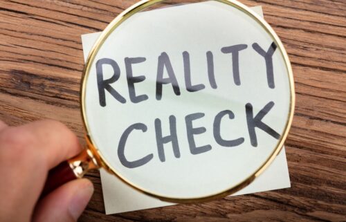 A magnifying glass focuses on a piece of paper with the handwritten words 