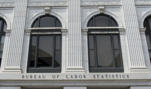 Exterior of Bureau of Labor Statistics (BLS) building featuring three tall arched windows with columns and classical details, creating a formal and authoritative tone.