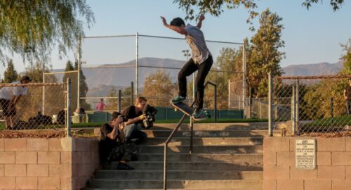 Skateboarder Martin Fobes performs a lipslide down a handrail at a public park, while being filmed by Chris Ray and photographed by Cameron Strand.