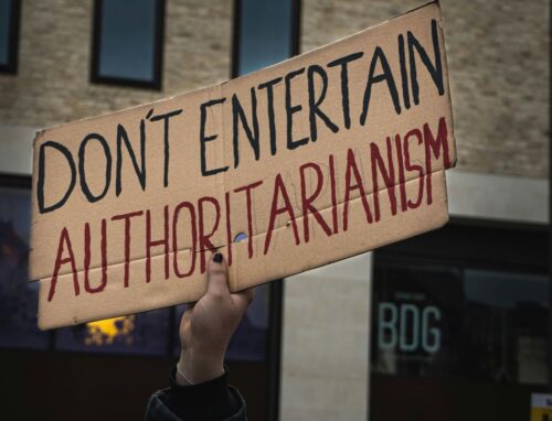 A protester holding a cardboard sign with the written words 