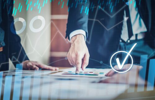 Business professionals in suits analyzing jobs documents with graphs overlaid; one hand points at data.