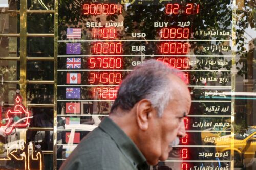 A man walks past an electronic board displaying currency exchange rates in Ferdowsi Square in the Iranian capital Tehran on September 28, 2025, Iran on September 28 condemned as 