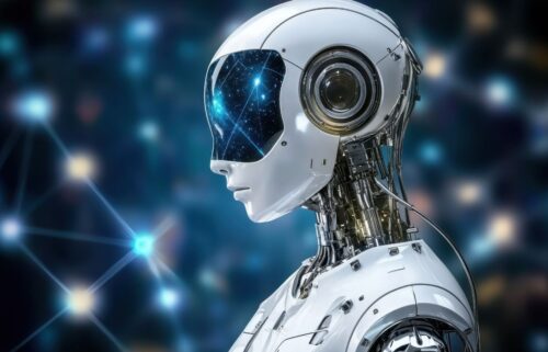 Futuristic humanoid robot with a sleek white exterior and a starry visor stands against a dark, blurred background of glowing nodes, conveying AI and artificial intelligence.