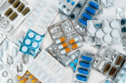 Various blister packs of pills scattered, featuring capsules in colors like blue, orange, and white, reflecting a clinical, organized tone. https://unsplash.com/photos/a-pile-of-pills-sitting-next-to-each-other-on-top-of-a-table-RS0-h_pyByk?utm_source=unsplash&utm_medium=referral&utm_content=creditShareLink