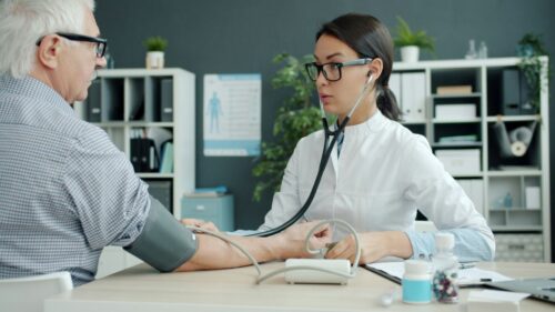 A female doctor measures an elderly man's blood pressure in a modern clinic. The setting is professional, conveying care and attentiveness. https://unsplash.com/photos/doctor-takes-elderly-patients-blood-pressure-96Eiu2AdZG0?utm_source=unsplash&utm_medium=referral&utm_content=creditShareLink