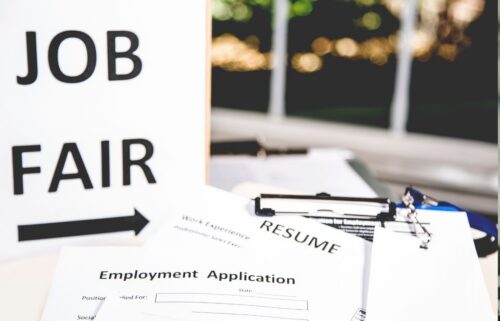 Stack of documents including a resume and employment application on a table, with a 