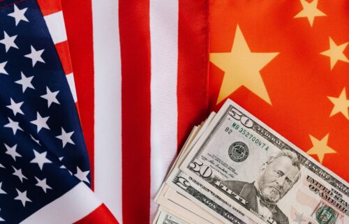 American and Chinese flags overlap beside a stack of US dollar bills.