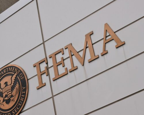 The image shows the FEMA logo on a building alongside the Department of Homeland Security emblem. The tone is formal and institutional.
