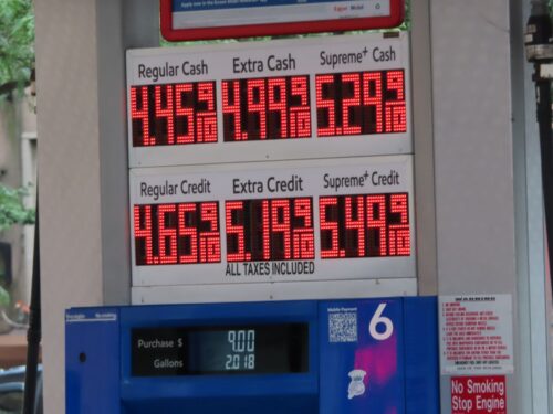 Gas station price board showing Regular Cash at $4.45, Extra Cash at $4.99, Supreme Cash at $5.29. Lower section lists credit prices.