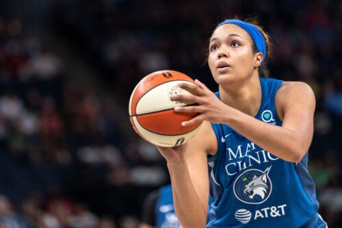WNBA player Napheesa Collier in a blue jersey prepares to shoot a free throw during a game. She looks focused and determined, with a crowded arena behind her. Photo by Lorie Shaull