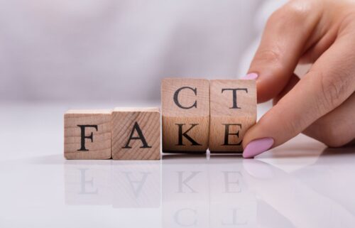 A hand with pink nails rotates a wooden block to change the word 