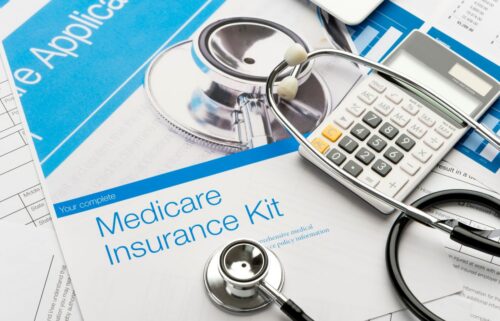 A stethoscope and calculator rest on a Medicare Insurance Kit document, suggesting healthcare and financial planning. The tone is professional and informative.