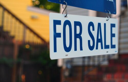 A for sale sign displayed in front of a house, indicating the property is available for purchase.